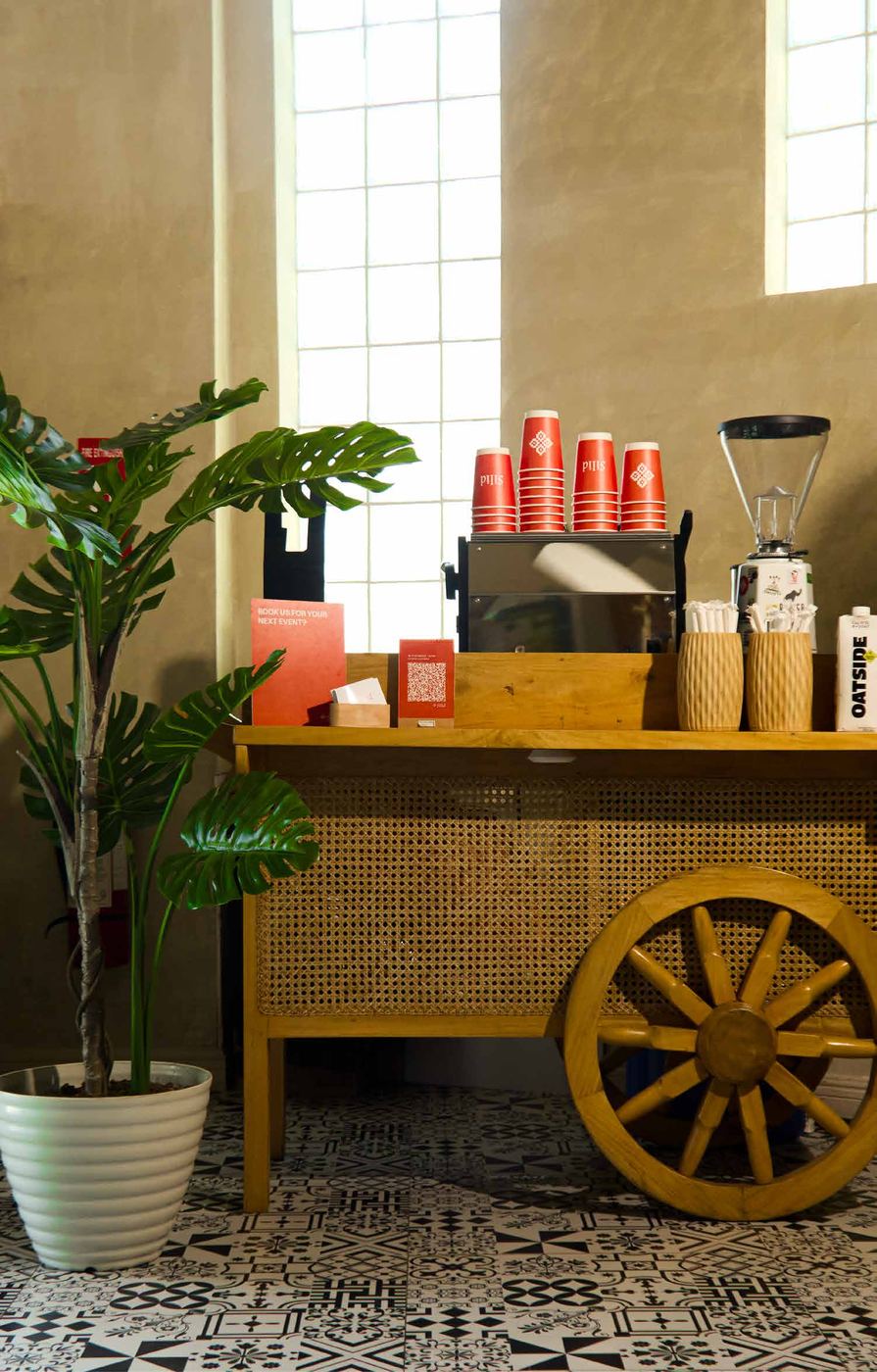 Silid's rattan-and-wood Kape Kariton coffee cart with a wagon wheel, espresso machine and stacked red Silid cups