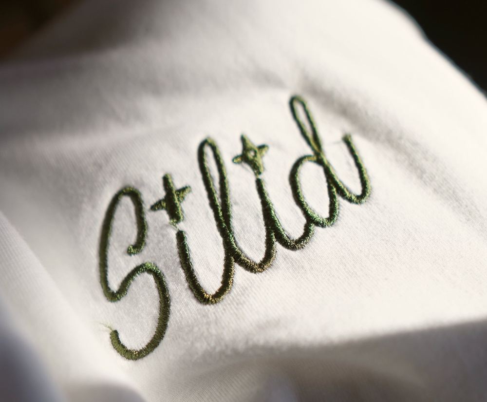 Silid logo embroidered in olive thread on a white shirt, made for the café's third anniversary